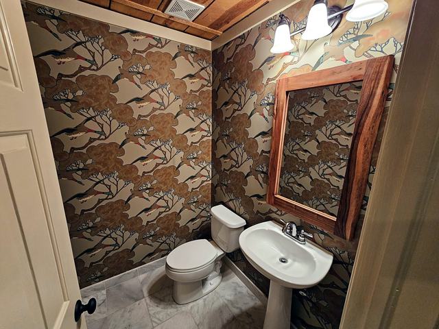 Copper branch powder room: Branch motif with a wood-framed mirror