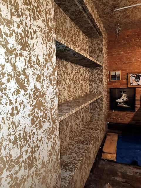 Metallic built-in: Torn-metal texture on a brick-wall bookcase