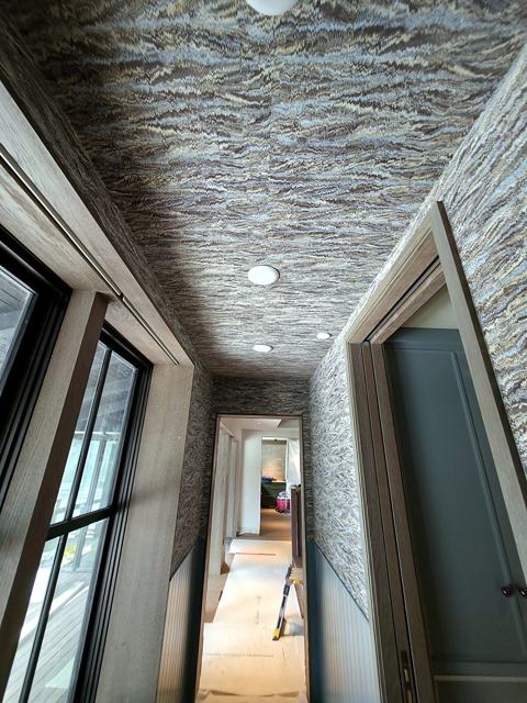 Strata-wrapped hallway: Stone-strata paper, walls to ceiling